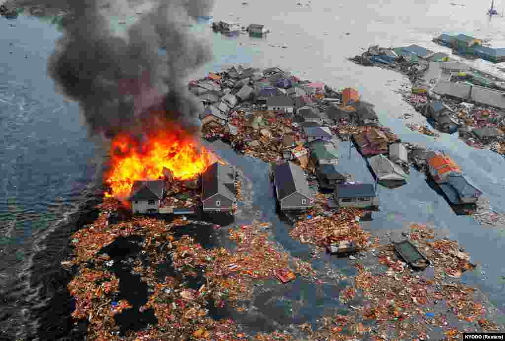 Цунами смывает дома в городе Натори на северо-востоке Японии. 11 марта 2011 года