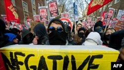 U.K. -- A demonstrator holds a giant replica textbook during a protest outside the University of London, on 09 December 2010