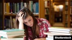 Generic -- (©Shutterstock) Student surrounded by books in a library